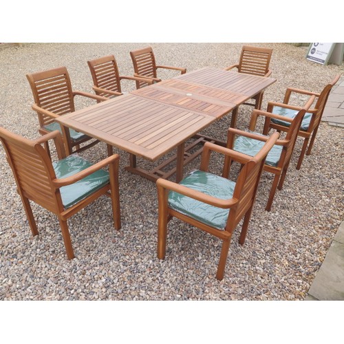 705 - A teak extending garden table with eight chairs and cushions - as new