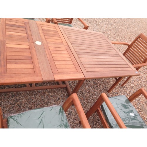 705 - A teak extending garden table with eight chairs and cushions - as new