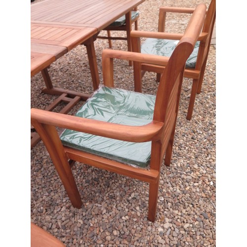 705 - A teak extending garden table with eight chairs and cushions - as new