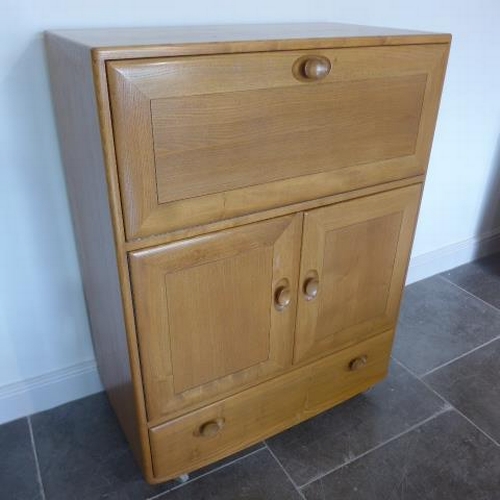 153 - An Ercol Golden Dawn blonde elm cabinet with a drop down front above two cupboard doors and a base d... 