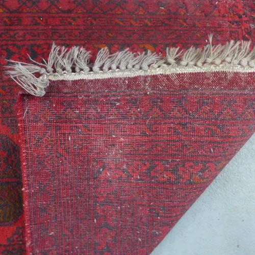 201 - A hand knotted woollen runner rug with a red field, 310cm x 82cm