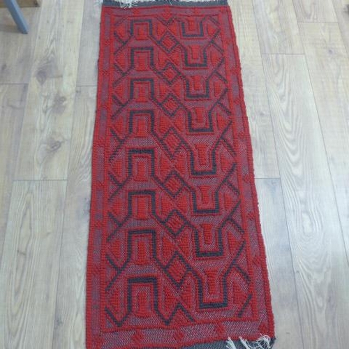 204 - A small rug with a red field, 155cm x 50cm
