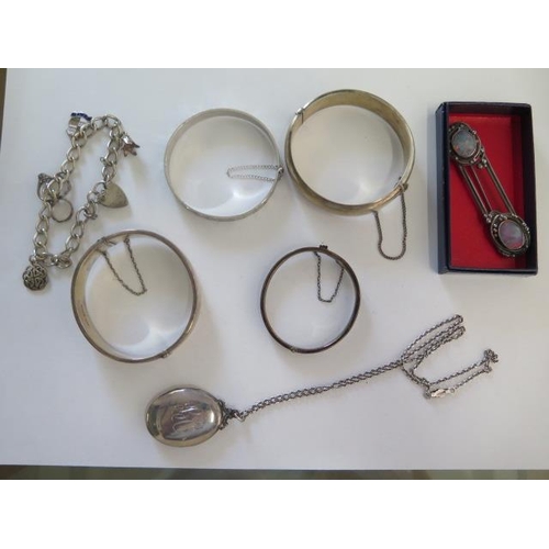 193 - Four silver bangles, a silver/white metal charm bracelet, locket and chain and a brooch - total weig... 