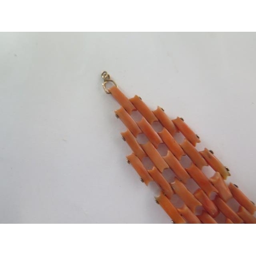 69 - A coral bracelet comprising four and three pinioned rectangular sections of coral to a large yellow ... 