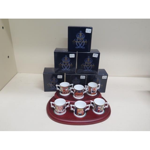 379 - A collection of Limited Edition Royal Crown Derby miniature loving cups on stand all no 102, good co... 