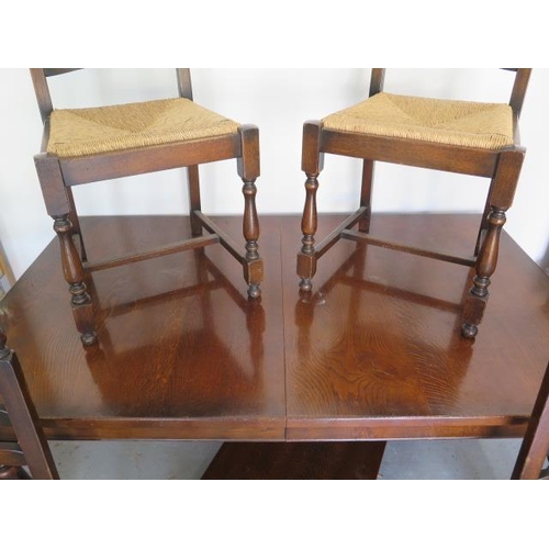 609 - An oak pull out dining table with one extra leaf and four rush seated chairs - Table 74cm tall x 91c... 