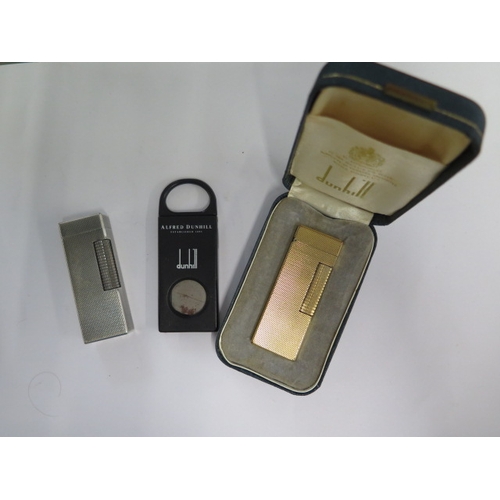 300 - Two Dunhill gas lighters, a plastic cigar cutter - one lighter boxed