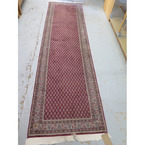 521 - A woollen runner with a red field - 310cm x 82cm - in good condition