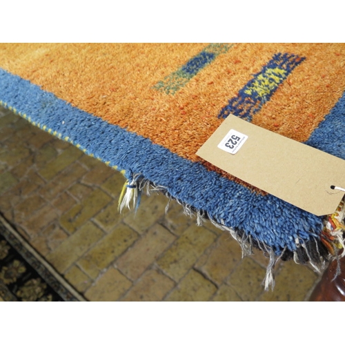 523 - A woollen rug with an orange field - some wear to edges - 197cm x 129cm