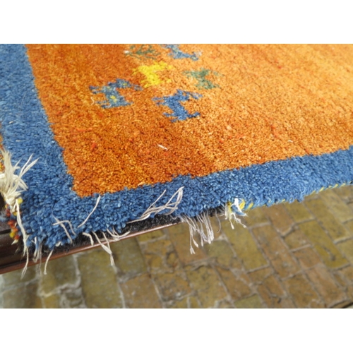 523 - A woollen rug with an orange field - some wear to edges - 197cm x 129cm