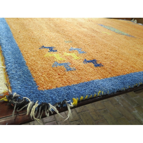 523 - A woollen rug with an orange field - some wear to edges - 197cm x 129cm