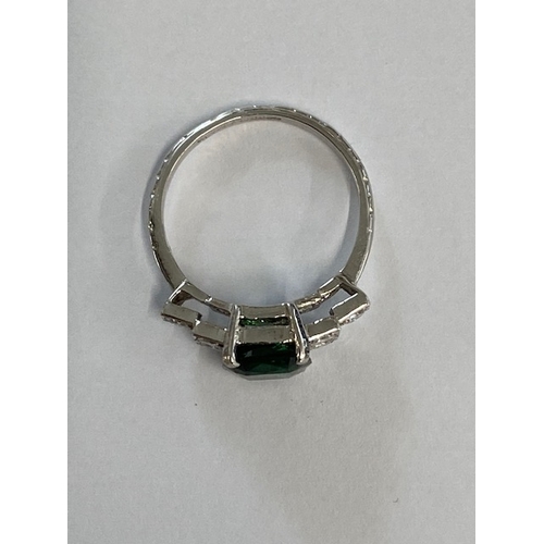 86 - A good platinum deep green Tsavorite and diamond ring - the central stone approx 3.02ct with six sur... 