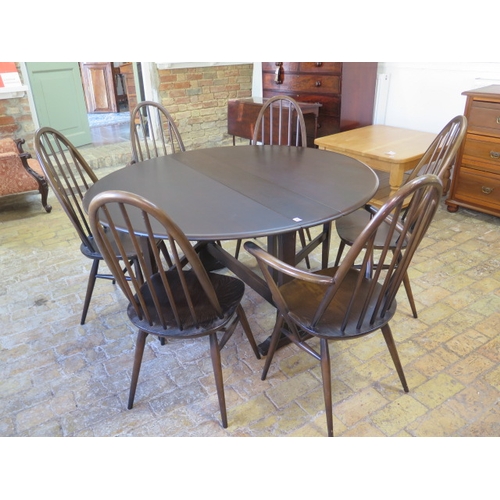 555 - An Ercol drop leaf dining table - Height 72cm x 128cm x 140cm extended with six stick back chairs in... 