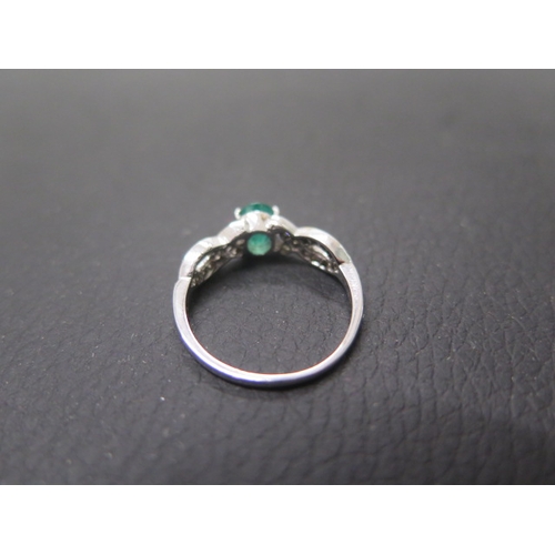 155 - An 18ct white gold emerald and diamond ring - The oval shaped emerald with diamond shoulders - ring ... 