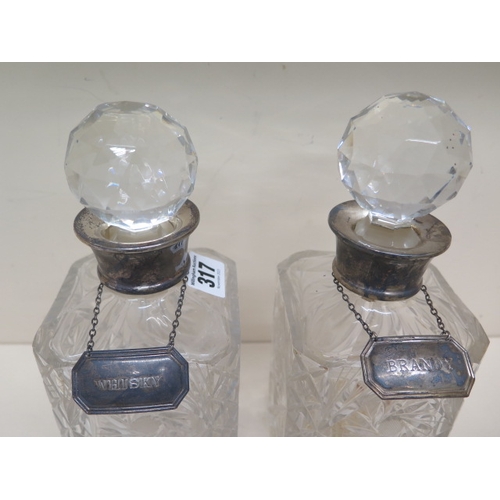 317 - A pair of silver topped cut glass decanters with silver Brandy and Whisky labels - one decanter with... 