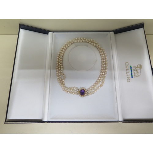 65 - A triple string pearl necklace with a 9ct yellow gold clasp set with central amethyst surrounded wit... 