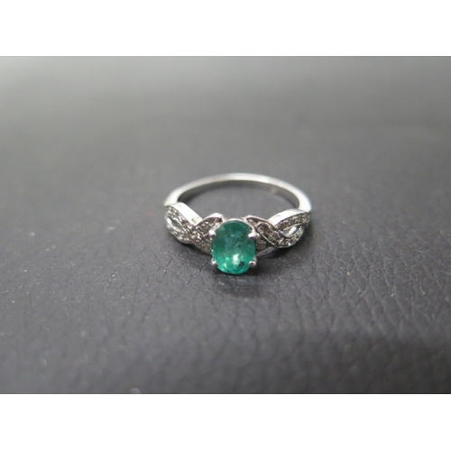 159 - An 18ct white gold emerald and diamond ring - The oval shaped emerald with diamond shoulders - ring ... 