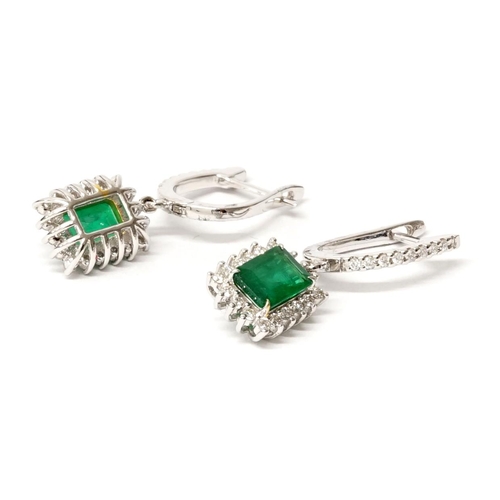 83 - A pair of 18ct white gold drop earrings set with emerald-cut emeralds, surrounded by round brilliant... 