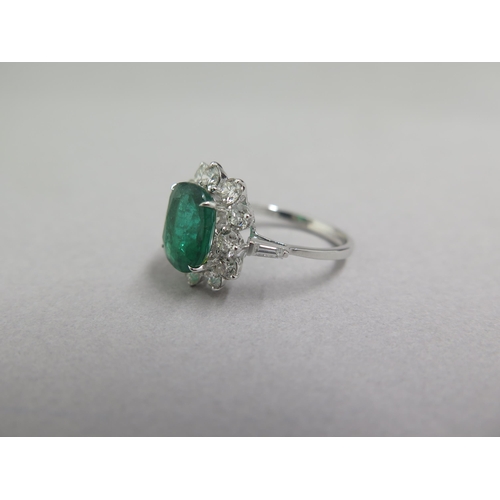 89 - An 18ct white gold ring set with oval cushion emerald and a halo of round brilliant cut diamonds, wi... 