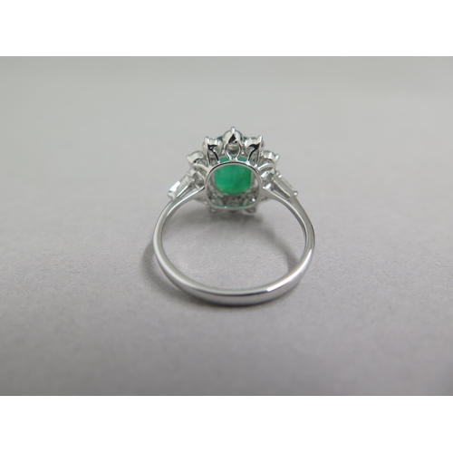 89 - An 18ct white gold ring set with oval cushion emerald and a halo of round brilliant cut diamonds, wi... 