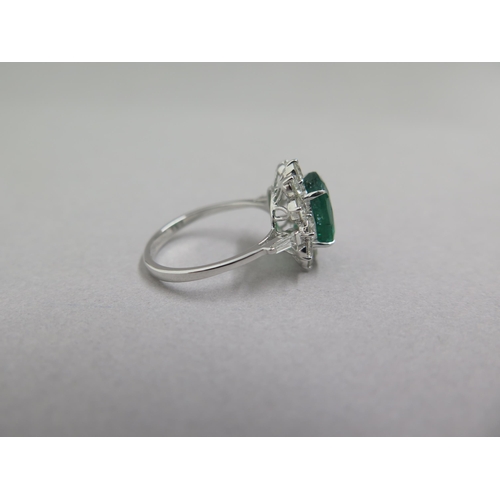 89 - An 18ct white gold ring set with oval cushion emerald and a halo of round brilliant cut diamonds, wi... 