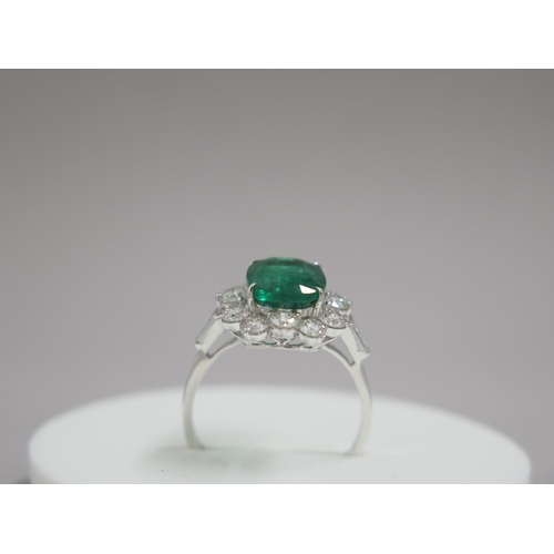 89 - An 18ct white gold ring set with oval cushion emerald and a halo of round brilliant cut diamonds, wi... 