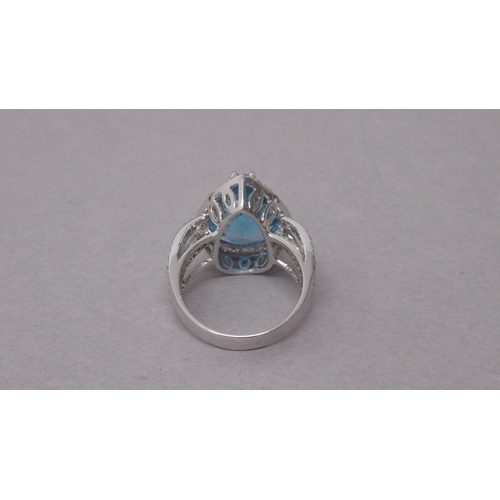 100 - An exciting 18ct white gold ring set with a pear-shaped blue topaz and halo of round brilliant cut d... 