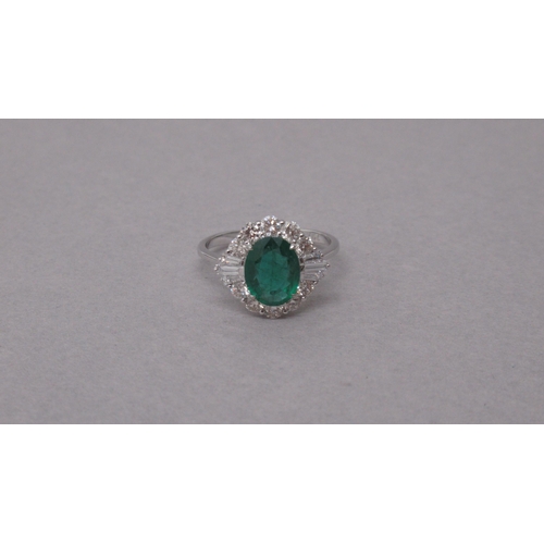 102 - An 18ct white gold ring set with an oval-cut emerald surrounded by a halo of diamonds - Emerald 1.38... 