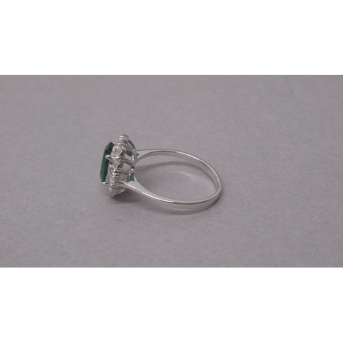 102 - An 18ct white gold ring set with an oval-cut emerald surrounded by a halo of diamonds - Emerald 1.38... 