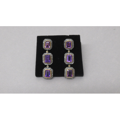 77 - A striking pair of silver-gilt drop earrings each set with 3 emerald-cut amethysts, each surrounded ... 