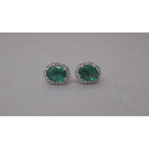 87 - A pair of 18ct white gold oval emerald and round brilliant cut diamond cluster studs, boxed - Emeral... 