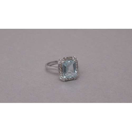 98 - An 18ct white gold ring set with a central emerald-cut aquamarine, with surrounding princess-cut dia... 