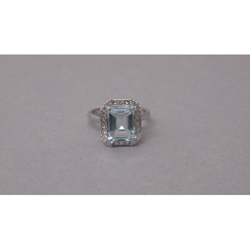 98 - An 18ct white gold ring set with a central emerald-cut aquamarine, with surrounding princess-cut dia... 