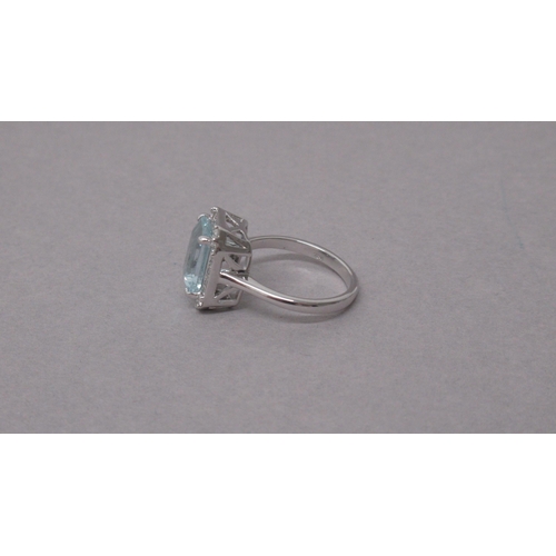 98 - An 18ct white gold ring set with a central emerald-cut aquamarine, with surrounding princess-cut dia... 