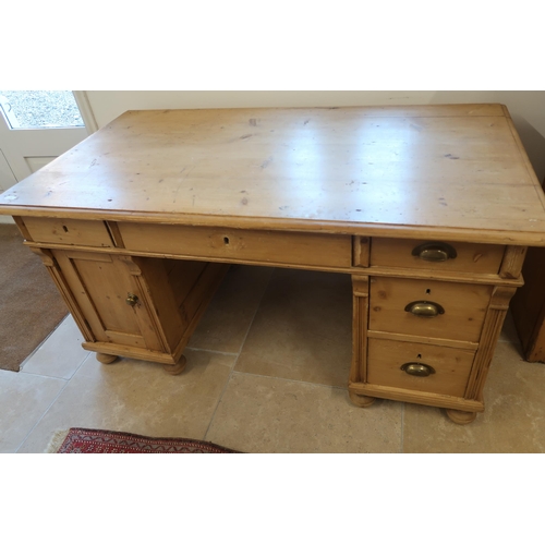 599 - A Continental pine desk with cupboards and drawers - Width 143cm x Depth 77cm x Height 74cm