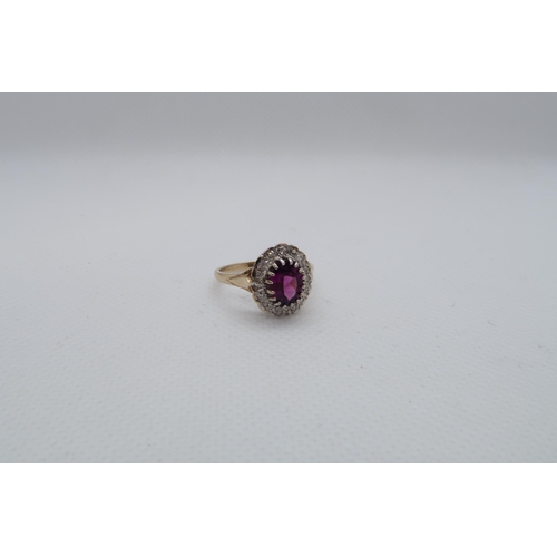 110 - A 9ct yellow and white gold dress ring set with a purplish red rhodolite garnet and a diamond halo, ... 