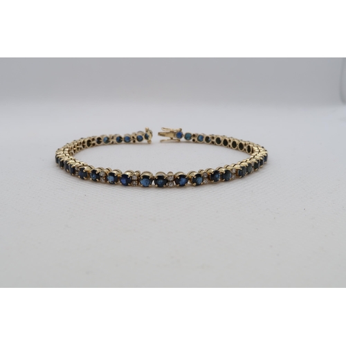 142 - An 18ct (hallmarked) yellow gold sapphire and diamond tennis bracelet - 42 blue sapphires in pairs a... 