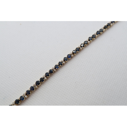 142 - An 18ct (hallmarked) yellow gold sapphire and diamond tennis bracelet - 42 blue sapphires in pairs a... 