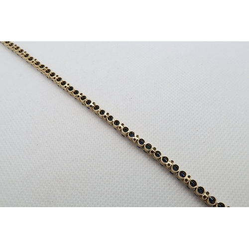 142 - An 18ct (hallmarked) yellow gold sapphire and diamond tennis bracelet - 42 blue sapphires in pairs a... 