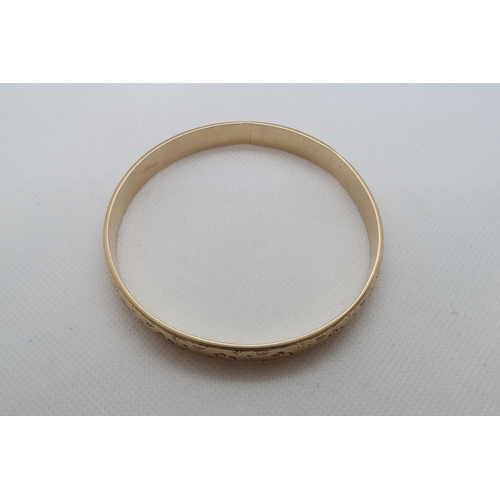 177 - A 9ct yellow gold (hallmarked) bangle with chased decoration - Diameter 7cm - weight approx 44.1 gra... 