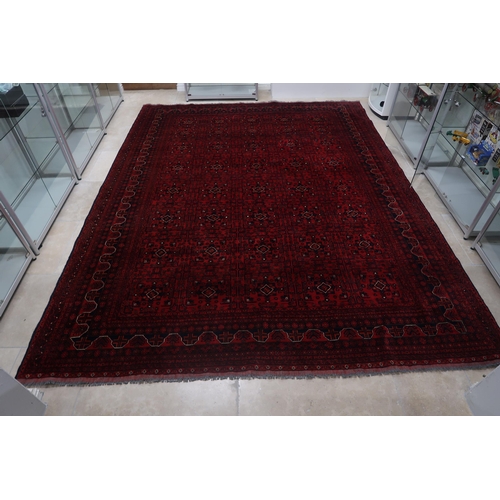 585 - A hand knotted Afgan rug - 4m x 3m - with a deep red field - in good condition and colours