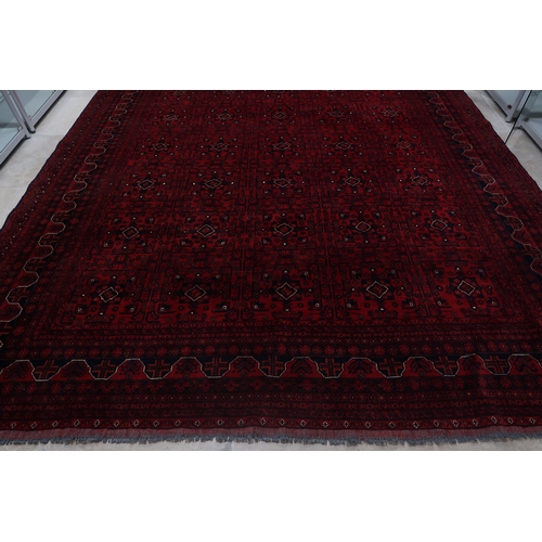 585 - A hand knotted Afgan rug - 4m x 3m - with a deep red field - in good condition and colours