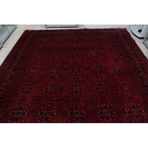 585 - A hand knotted Afgan rug - 4m x 3m - with a deep red field - in good condition and colours