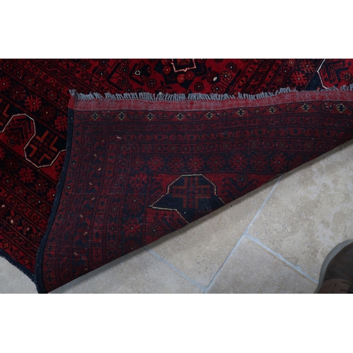 585 - A hand knotted Afgan rug - 4m x 3m - with a deep red field - in good condition and colours