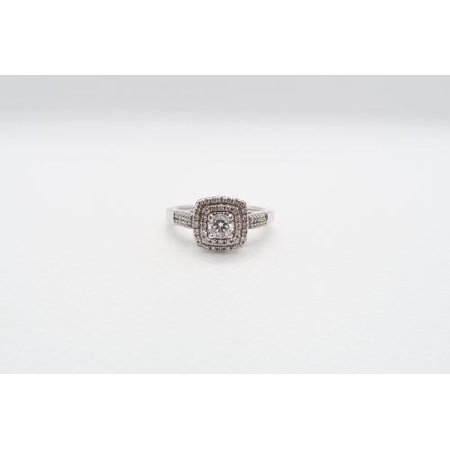 An 18ct white gold and diamond cluster ring - The central round brilliant cut diamond approx 0.25ct with double halo of round brilliant cut diamonds and shoulders with twin rows of diamonds - ring size K/L - weight approx 5.2 grams