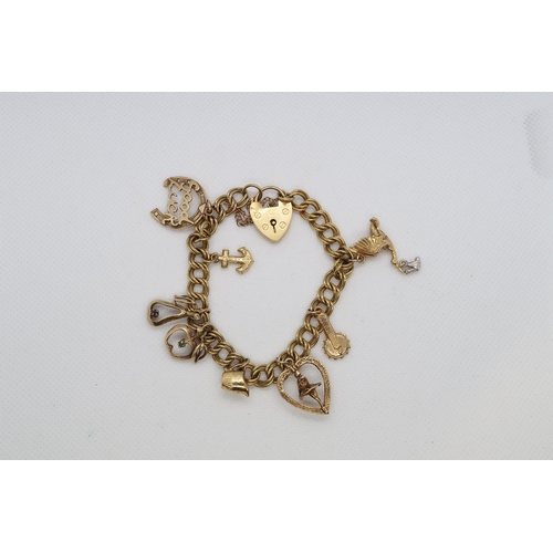 98 - A 9ct yellow gold (hallmarked) charm bracelet - 8 charms with heart lock - approx weight 24.4 grams