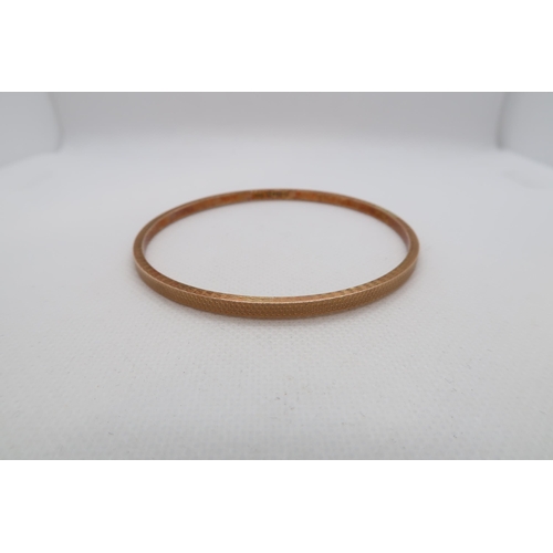 215 - A 9ct gold (hallmarked) bangle with machined decoration - Diameter 7.5cm - approx weight 6.3 grams