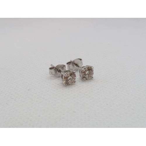 184 - A pair of single stone diamond stud earrings - studs set in 18ct white gold - each round brilliant c... 