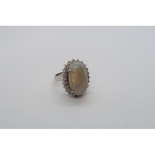 173 - A certified platinum dress ring set with an oval cabochon white opal surrounded by a halo of round b... 