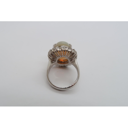 173 - A certified platinum dress ring set with an oval cabochon white opal surrounded by a halo of round b... 